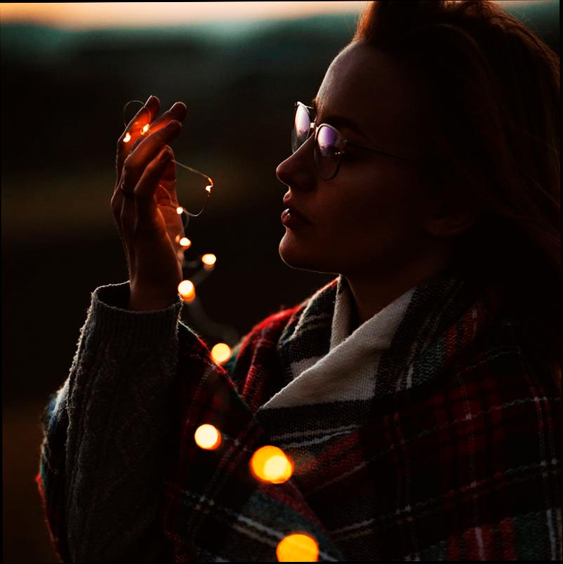 Foto de una mujer sosteniendo una cadena de luces.