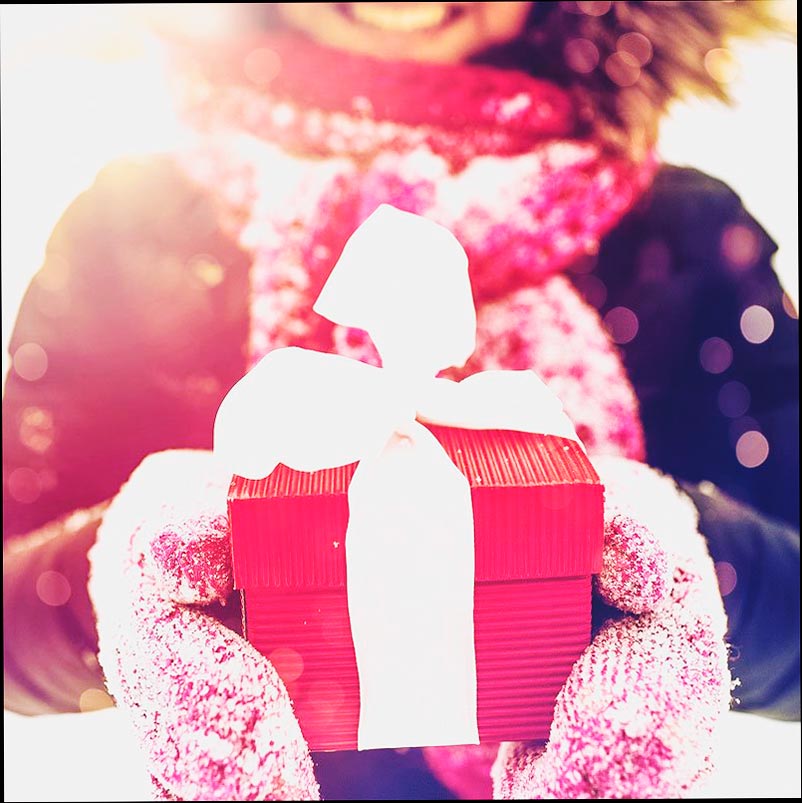 Cerca de una mujer sosteniendo una caja de regalo roja con una cinta blanca.