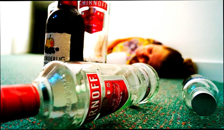 Hombre acostado detrás de botellas de alcohol