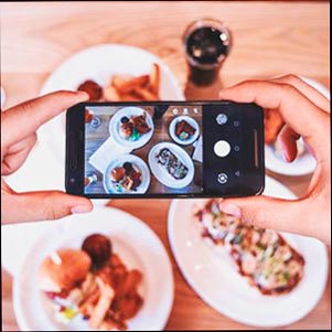 Foto de un comensal tomando una foto de su comida en un restaurante